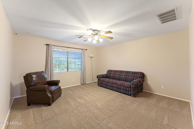 living area with visible vents, baseboards, carpet, and ceiling fan