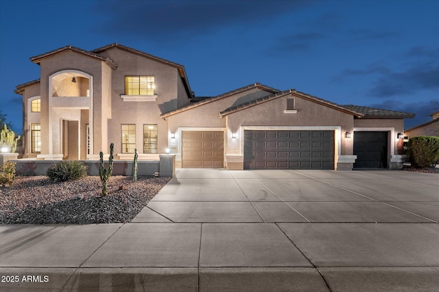 view of front of property featuring stucco siding, concrete driveway, an attached garage, and a tile roof