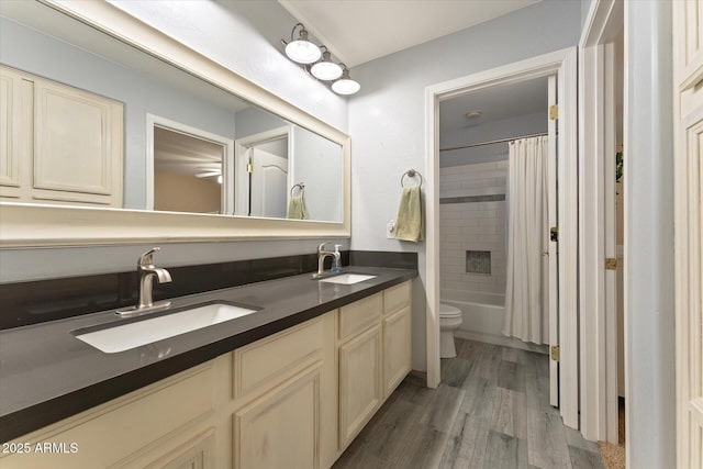 bathroom with a sink, toilet, wood finished floors, and double vanity