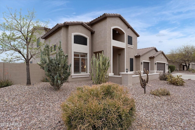 view of front of house with stucco siding, fence, a garage, and a tiled roof