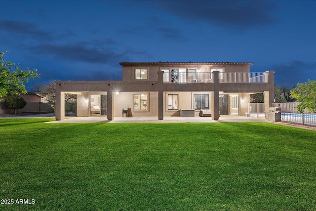 rear view of property with a patio, a balcony, a yard, and a fenced in pool