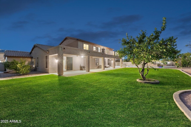 back of property with a patio area, stucco siding, and a yard