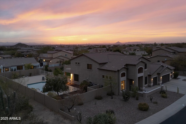 view of front of house with a residential view, a tile roof, stucco siding, a fenced backyard, and driveway