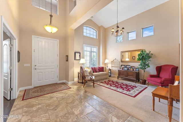 entryway with an inviting chandelier, a high ceiling, stone finish flooring, and baseboards