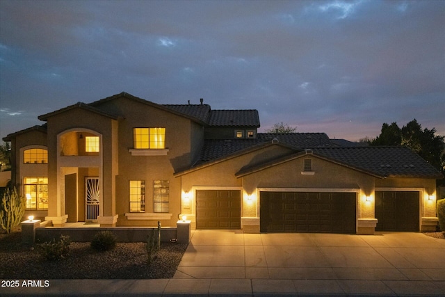 view of front of house with a tiled roof, stucco siding, driveway, and a garage