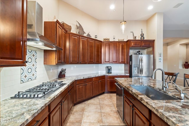 kitchen with stainless steel appliances, sink, light stone counters, and wall chimney exhaust hood