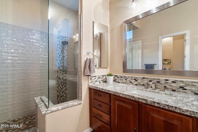 bathroom featuring vanity, a tile shower, and backsplash