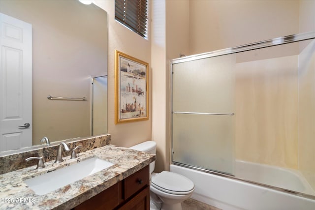 full bathroom with vanity, bath / shower combo with glass door, and toilet