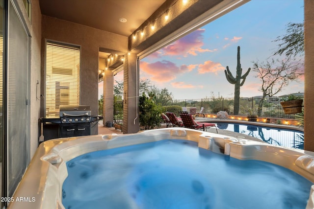 pool at dusk with a grill and a hot tub