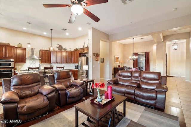 tiled living room with ceiling fan with notable chandelier