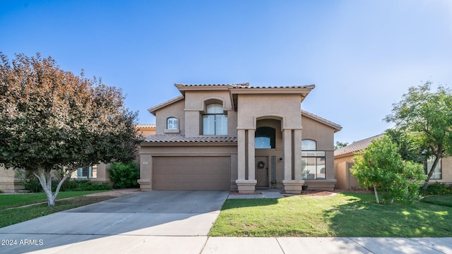 mediterranean / spanish home with a garage and a front lawn