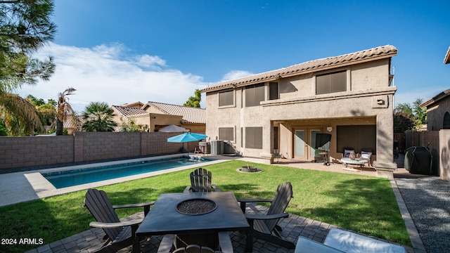 rear view of house featuring a patio, a fenced in pool, a fire pit, and a lawn