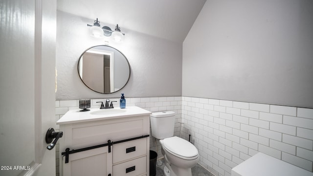 bathroom with vanity, toilet, tile walls, and lofted ceiling