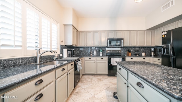 kitchen with sink, dark stone countertops, decorative backsplash, light tile patterned floors, and black appliances