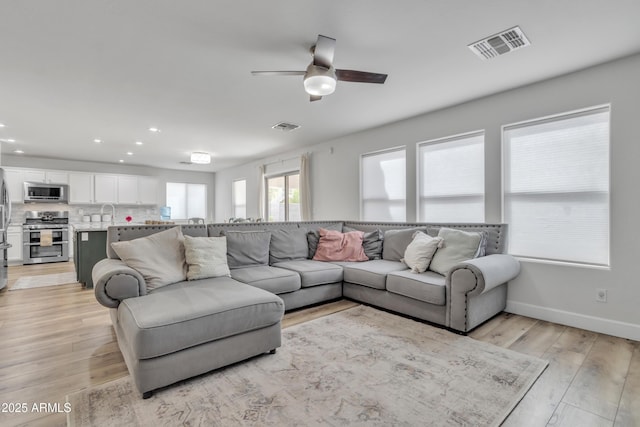 living area with recessed lighting, visible vents, light wood-style flooring, and baseboards