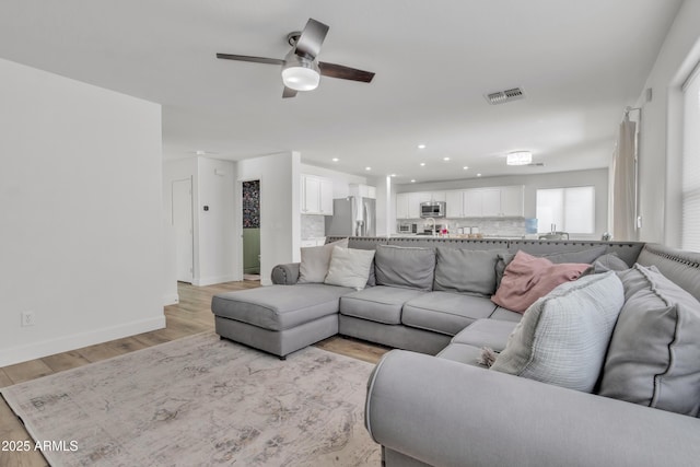 living room with recessed lighting, a ceiling fan, visible vents, baseboards, and light wood-type flooring