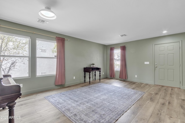 foyer entrance with visible vents, light wood-style flooring, and baseboards