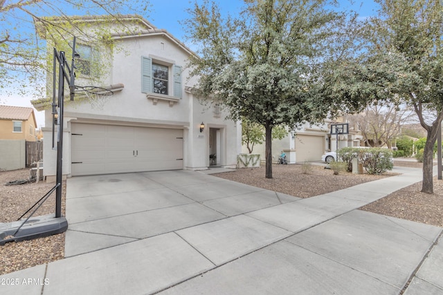 view of front of house with driveway, fence, an attached garage, and stucco siding