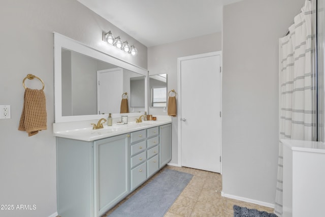 full bathroom featuring double vanity, a shower with curtain, a sink, and baseboards