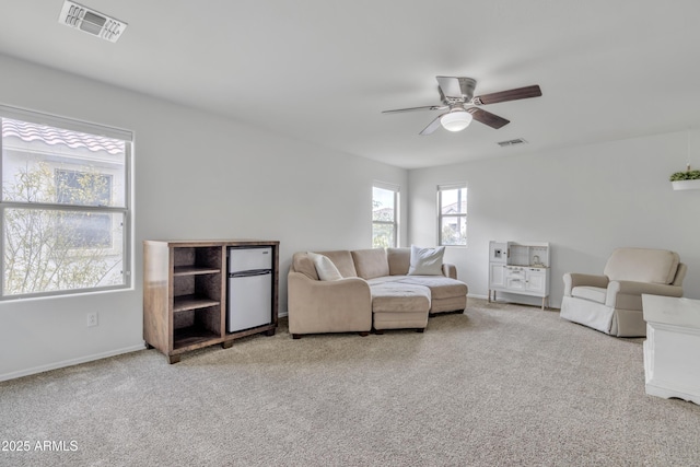 living room featuring baseboards, ceiling fan, visible vents, and carpet flooring