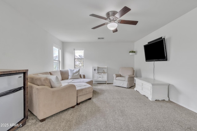 carpeted living room with ceiling fan and visible vents