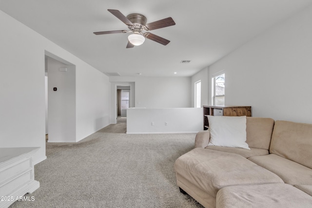 living area with visible vents, ceiling fan, and light carpet