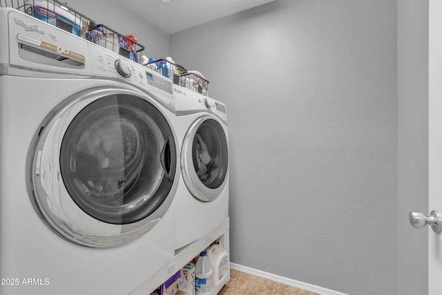 laundry area with laundry area, washing machine and clothes dryer, and baseboards