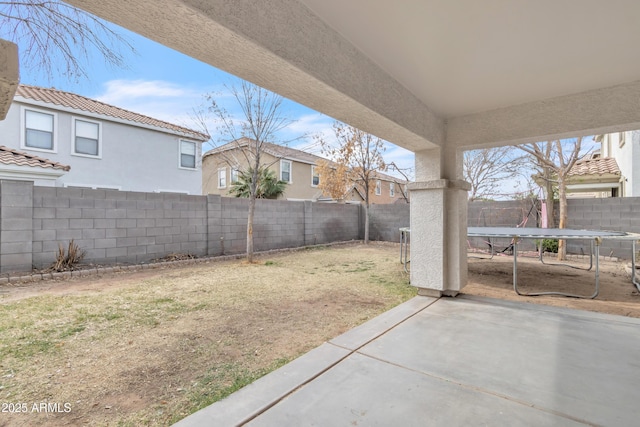 view of yard featuring a patio, a trampoline, and a fenced backyard