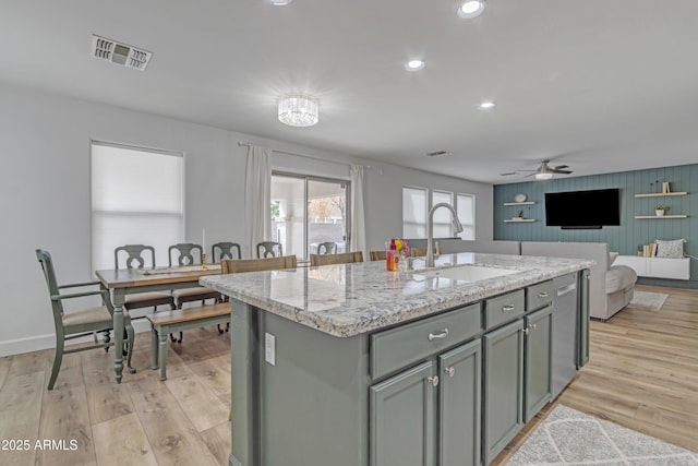 kitchen with visible vents, dishwasher, gray cabinetry, light wood-type flooring, and a sink