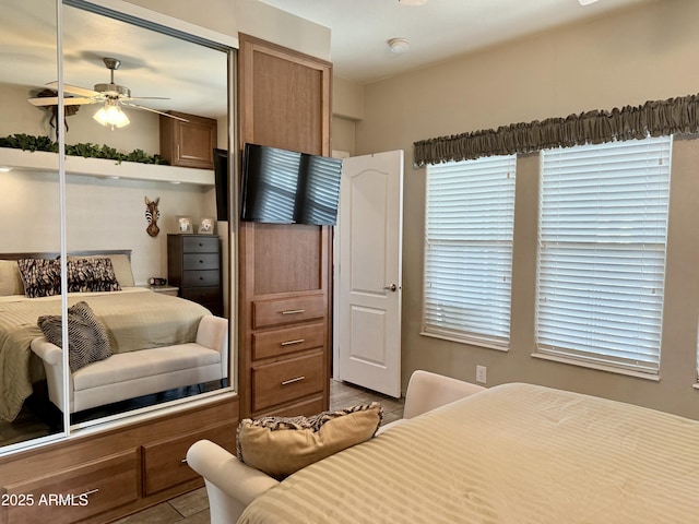 bedroom with multiple windows, ceiling fan, a closet, and light tile patterned floors