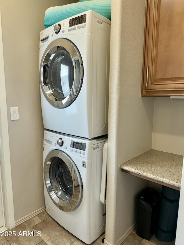 washroom with cabinets, light tile patterned floors, and stacked washing maching and dryer