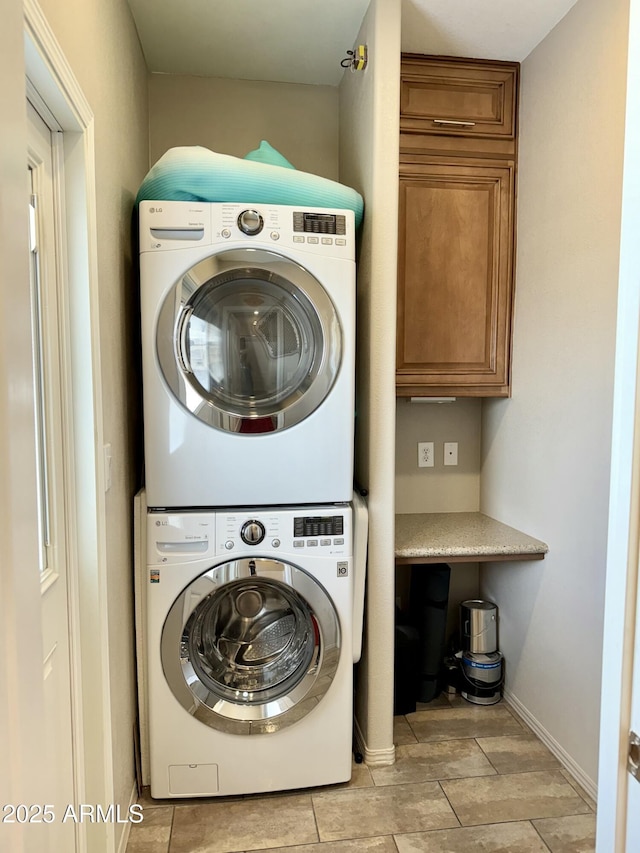 washroom with cabinets and stacked washer / dryer