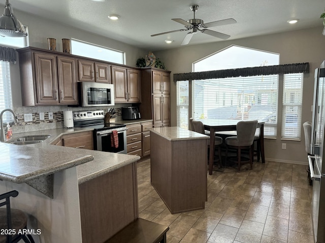 kitchen with sink, a center island, tasteful backsplash, pendant lighting, and appliances with stainless steel finishes