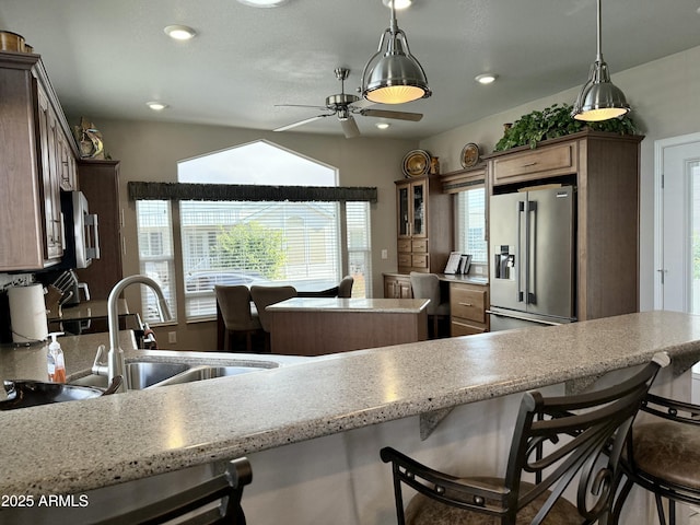 kitchen with pendant lighting, sink, ceiling fan, a kitchen bar, and stainless steel appliances