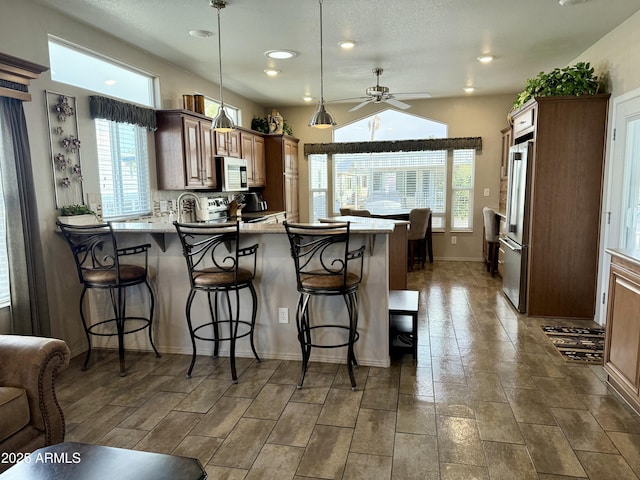 kitchen with ceiling fan, stainless steel appliances, kitchen peninsula, pendant lighting, and a breakfast bar area