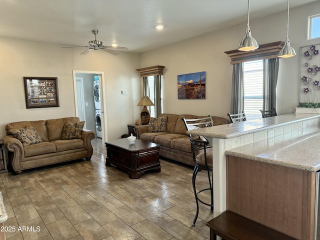 living room featuring ceiling fan and stacked washer / drying machine