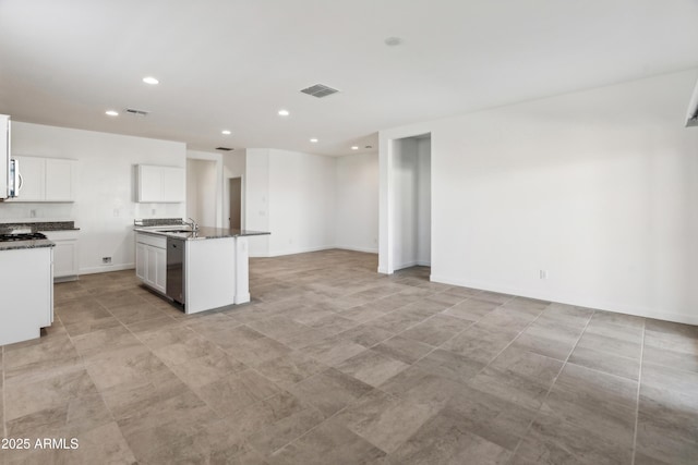 kitchen with dishwasher, sink, white cabinetry, dark stone countertops, and a center island with sink