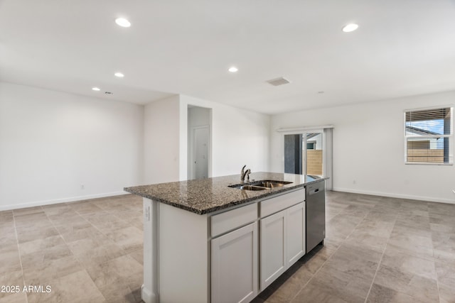 kitchen with sink, dishwasher, a kitchen island with sink, and dark stone counters