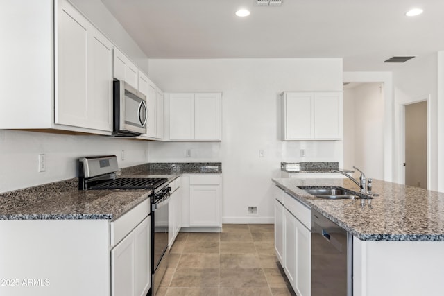 kitchen featuring sink, dark stone countertops, white cabinets, and appliances with stainless steel finishes