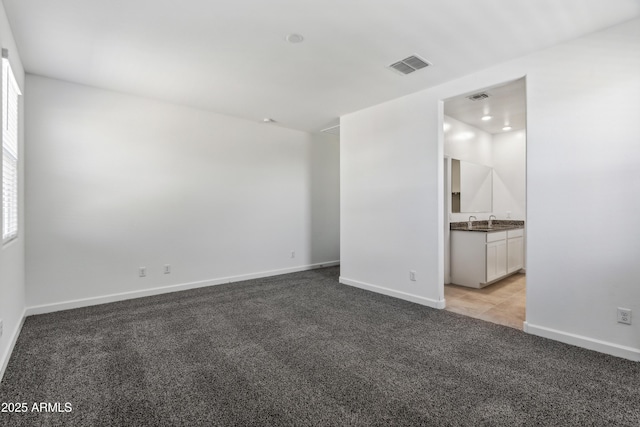 spare room with sink and light carpet