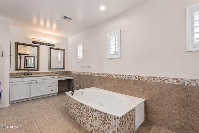 bathroom with tile patterned floors, vanity, a bathing tub, and tile walls