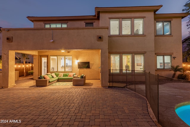 back house at dusk featuring a patio area and an outdoor hangout area