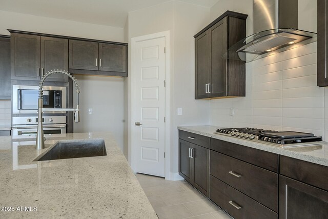 kitchen with light stone countertops, wall chimney exhaust hood, light tile patterned floors, decorative backsplash, and appliances with stainless steel finishes