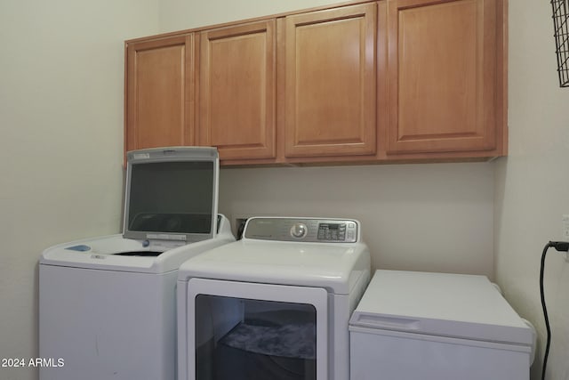 clothes washing area with washing machine and clothes dryer and cabinets