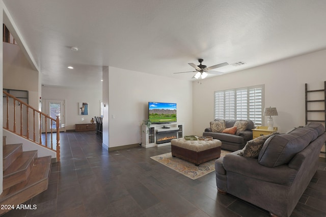 living room with a wealth of natural light, a fireplace, dark hardwood / wood-style flooring, and ceiling fan