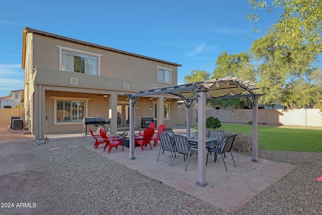 back of property with a pergola, a patio area, central AC, and a lawn