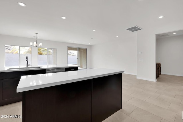 kitchen featuring a center island, sink, hanging light fixtures, stainless steel dishwasher, and a chandelier