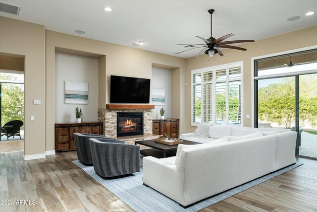 living room featuring ceiling fan, hardwood / wood-style flooring, and a fireplace