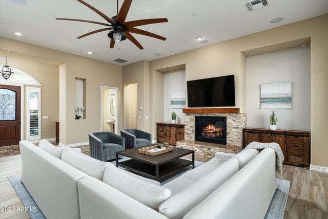 living room with light wood-type flooring, a fireplace, and ceiling fan