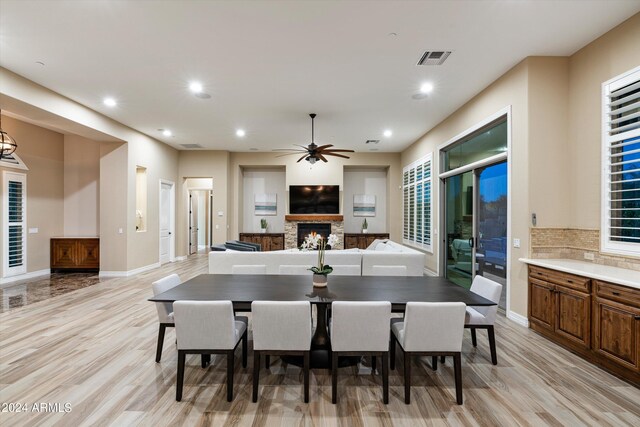 dining space featuring light hardwood / wood-style flooring, ceiling fan, and a fireplace